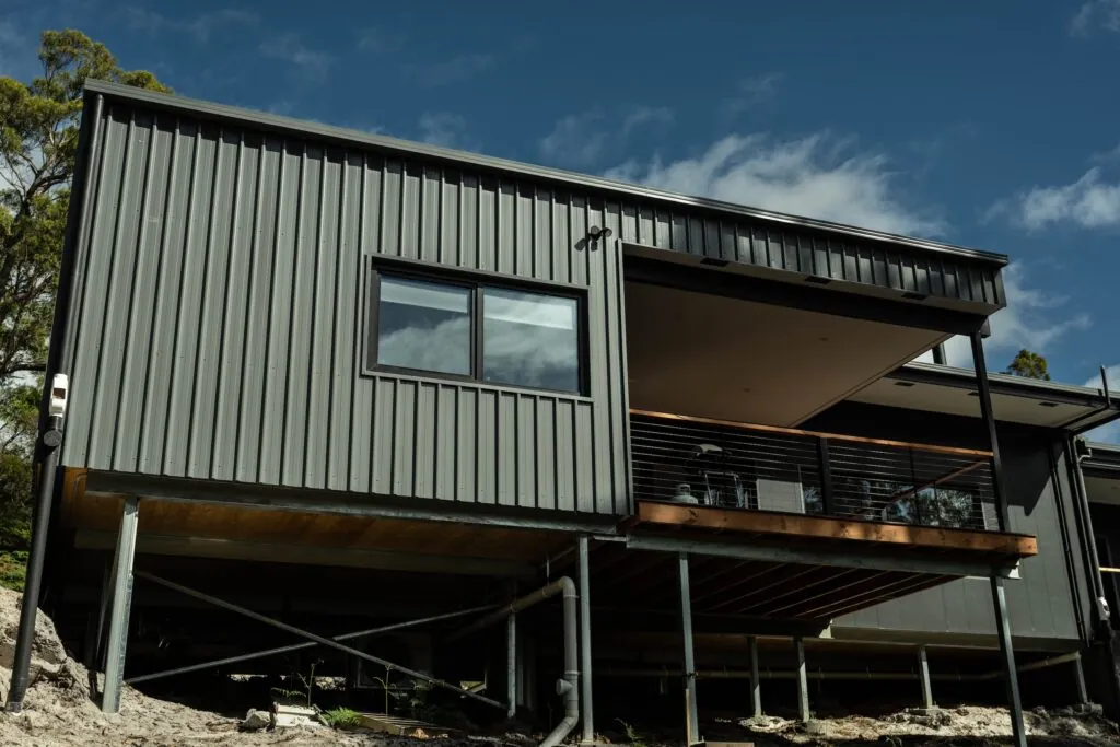 An image of a grey modular home with a deck