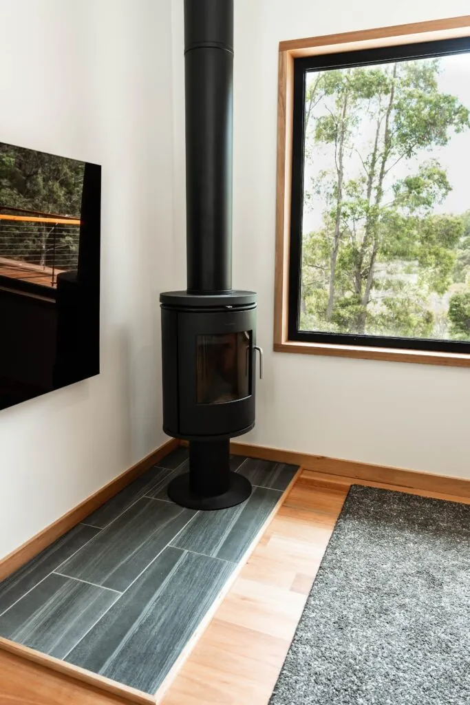 Wood fire heater next to tv and window in modular home living room